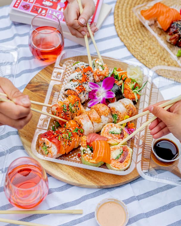 Friends sharing a sushi platter with rosé