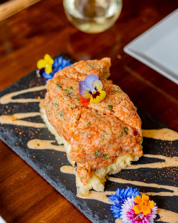 Pressed sushi with spicy tartare and a pansy on a slate plate