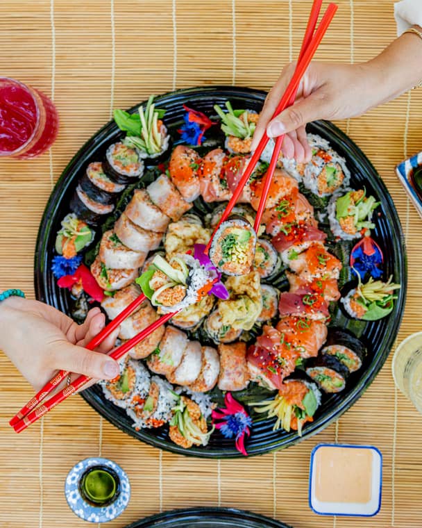Guests reaching for sushi on a round platter